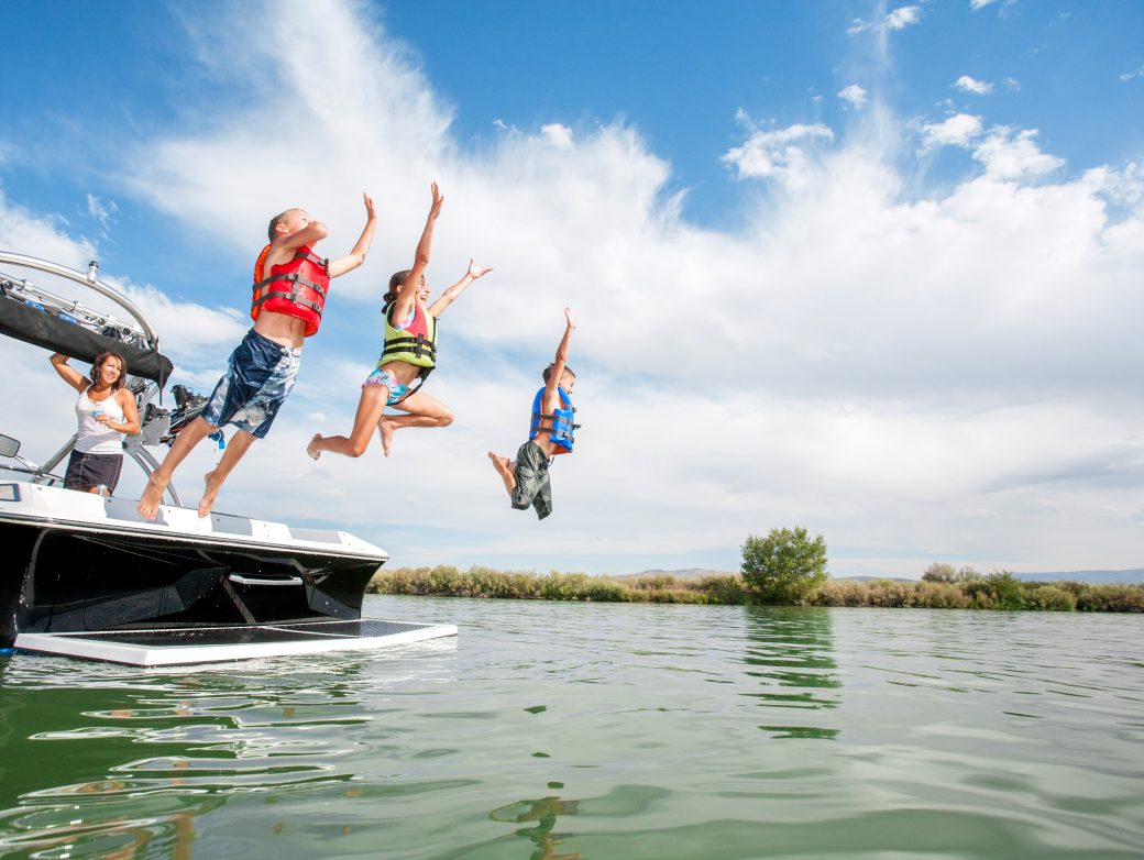 Children jumping off boat into lake